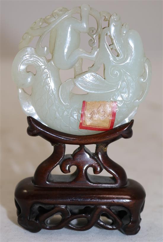 A Chinese pale celadon jade fish-dragon and boy disc, 18th century, diameter 6.1cm, rosewood stand